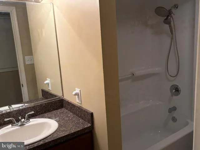 a bathroom with a granite countertop sink a mirror and shower