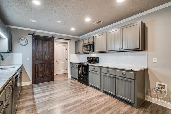 a kitchen with stainless steel appliances granite countertop a refrigerator a sink dishwasher and wooden cabinets with wooden floor