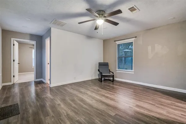 a view of an empty room with a window and wooden floor