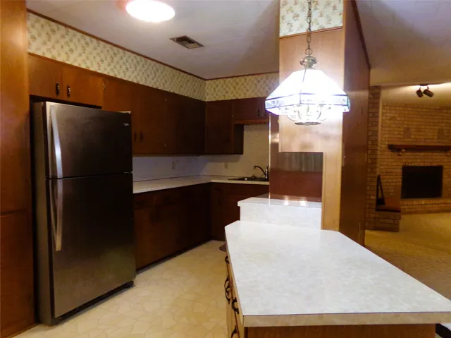 a kitchen with granite countertop a refrigerator a stove a sink and a dining table