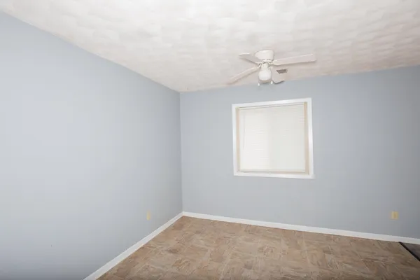 an empty room with a window and a fan