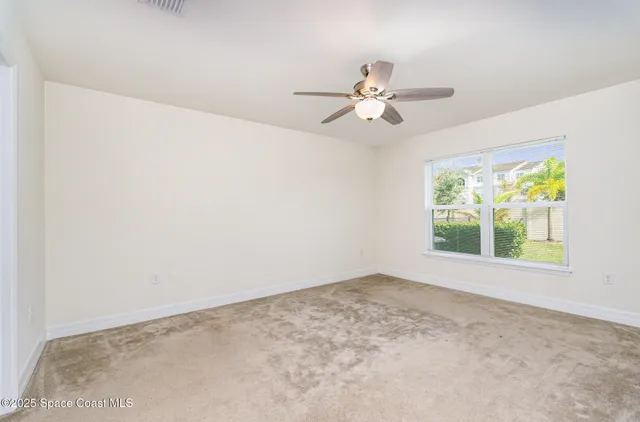 an empty room with a window and a fan