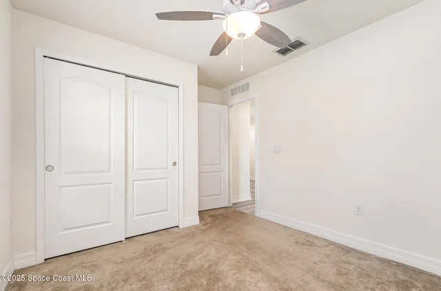 an empty room with closet and a chandelier fan
