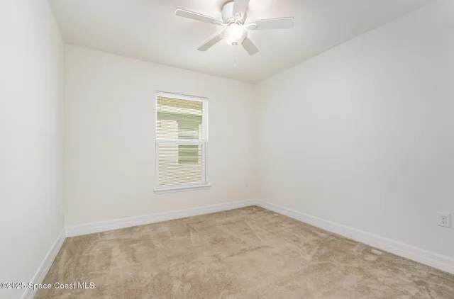 an empty room with a window and a fan