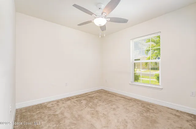 an empty room with a window and a ceiling fan