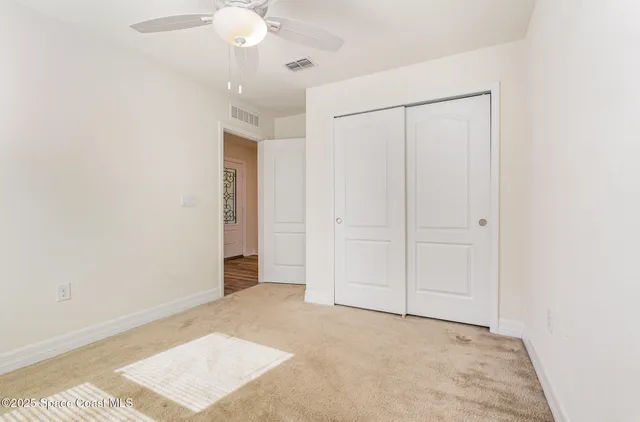 an empty room with closet and a chandelier fan