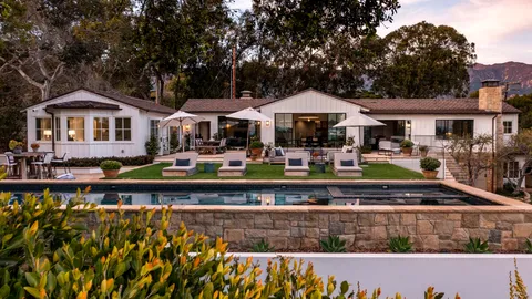 a front view of a house with swimming pool and chairs