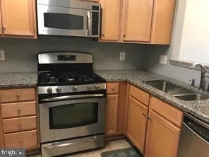 a kitchen with granite countertop white cabinets stainless steel appliances and a sink