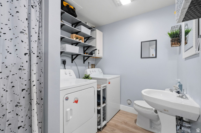 1099 South 950 East, Unit 17 Provo, UT 84606 - Photo 16 of 23 Compact utility space featuring wood-finish flooring, a white pedestal sink, a toilet, and integrated laundry appliances