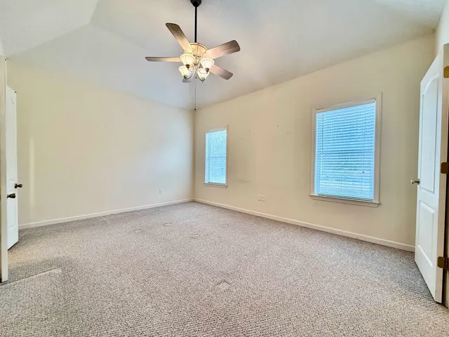 a view of an empty room with a chandelier fan