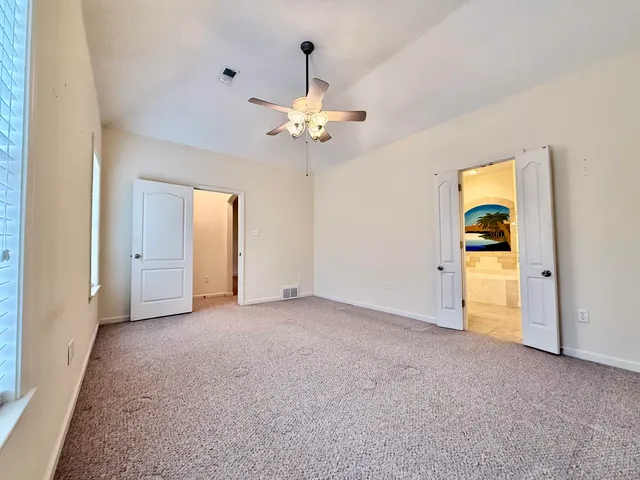 a view of an empty room with chandelier fan and a window
