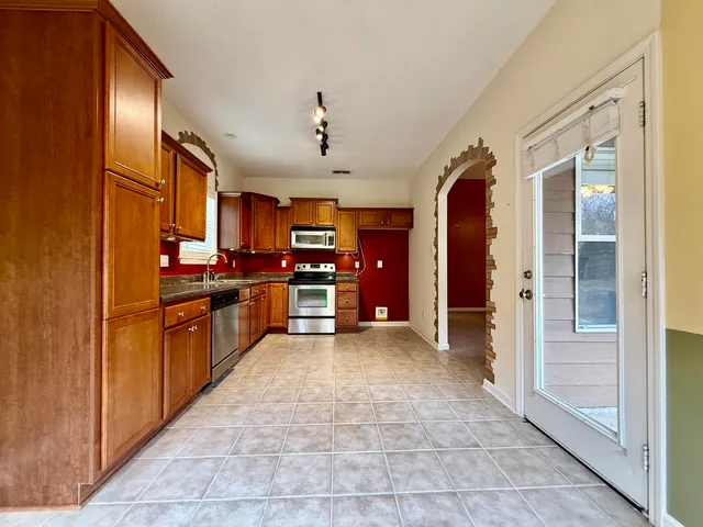 a large kitchen with stainless steel appliances granite countertop a refrigerator and cabinets