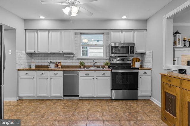 a kitchen with granite countertop a stove top oven a sink a counter space and cabinets