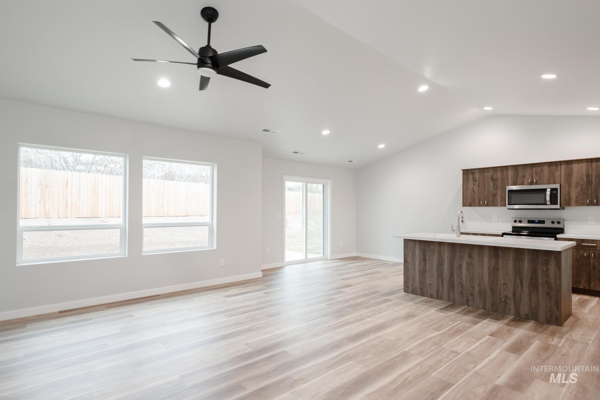 1576 Long Pond Street Middleton, ID 83644 - Photo 21 of 22 Kitchen featuring an island with sink, open floor plan, lofted ceiling, stainless steel appliances, and light wood-style floors