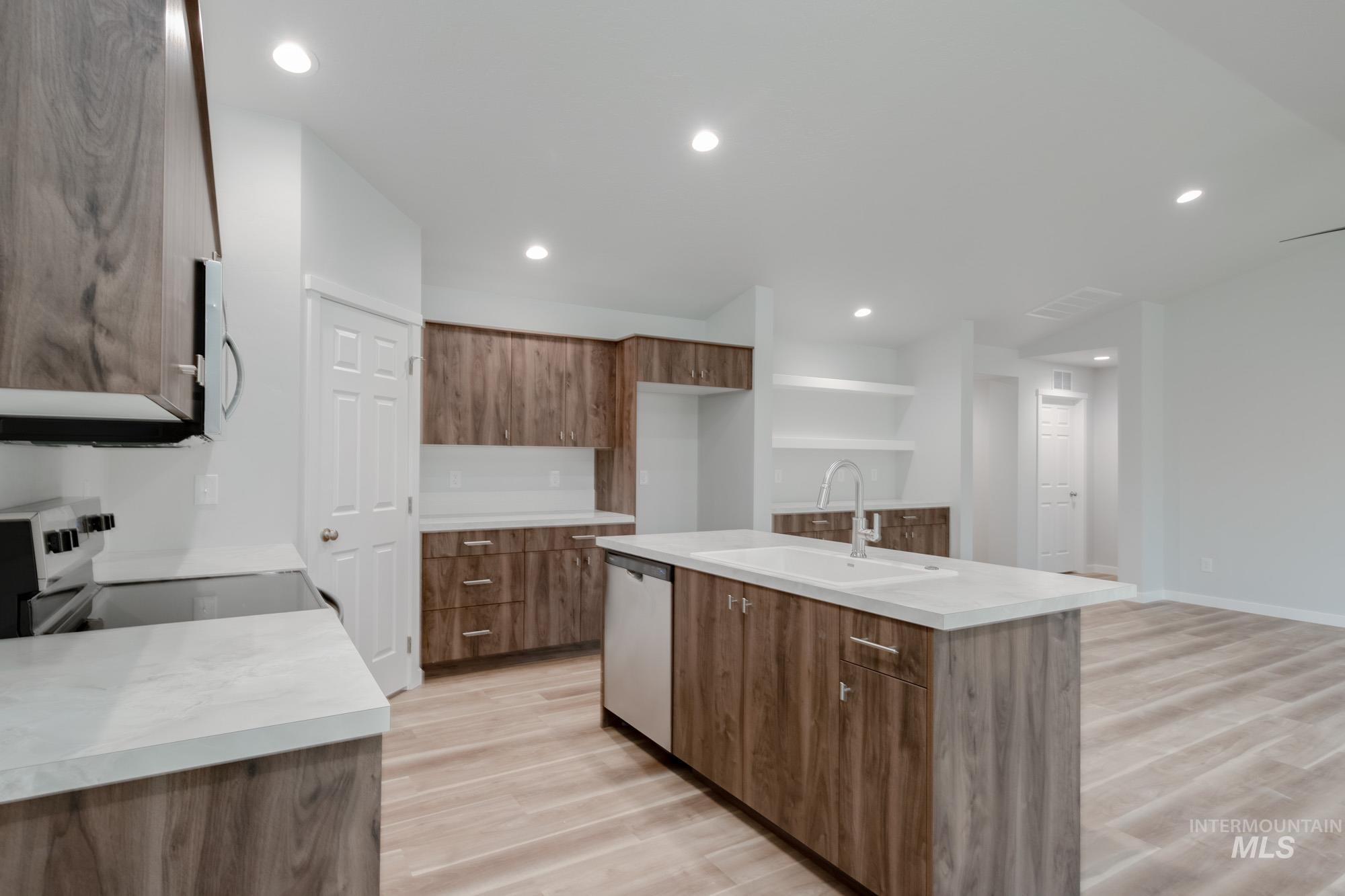 1576 Long Pond Street Middleton, ID 83644 - Photo 8 of 22 Kitchen with light wood-style floors, brown cabinetry, stainless steel appliances, a kitchen island with sink, and recessed lighting