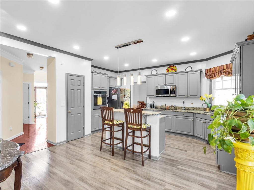 2354 Brentmoore Point Conyers, GA 30013 - Photo 21 of 91 a kitchen with stainless steel appliances kitchen island granite countertop a refrigerator a stove a dining table and chairs with wooden floor