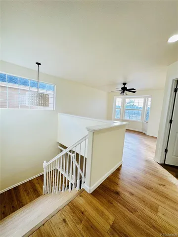 an empty room with wooden floor and ceiling fan