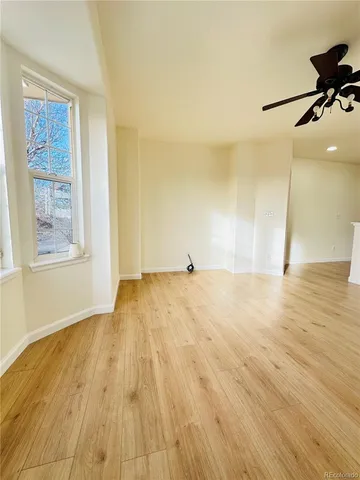 a view of an empty room with window and wooden floor