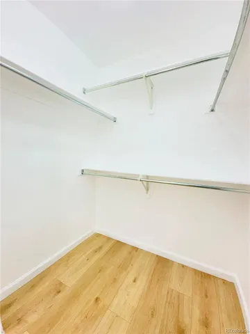 a view of empty room with wooden floor and window