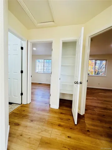 a view of an empty room with wooden floor and a window
