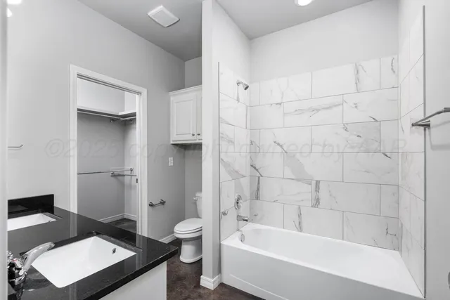 a bathroom with a granite countertop bathtub shower sink vanity and toilet