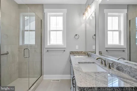 a bathroom with a granite countertop tub sink and mirror