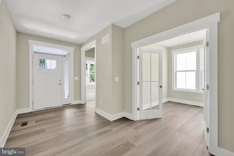 an empty room with wooden floor & windows