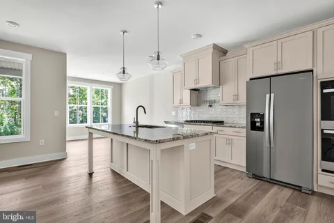 a kitchen with stainless steel appliances granite countertop a refrigerator a sink dishwasher a oven with white cabinets and wooden floor