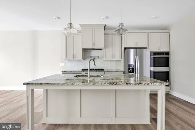 a kitchen with kitchen island granite countertop a sink cabinets and stainless steel appliances