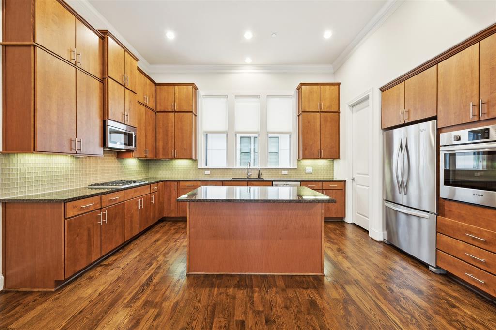 2134 Canton Street Dallas, TX 75201 - Photo 8 of 34 Kitchen featuring appliances with stainless steel finishes, ornamental molding, a center island, tasteful backsplash, and dark stone counters