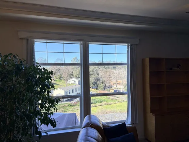 a view of a dining room and livingroom with furniture wooden floor a rug and a large window