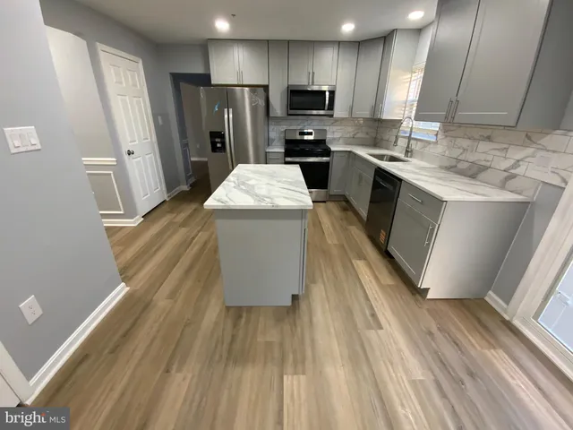 a kitchen with a sink dishwasher refrigerator stove and wooden floor