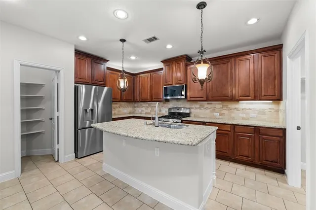 a kitchen with kitchen island granite countertop appliances cabinets a sink and a counter top space