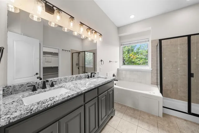 a bathroom with a granite countertop bathtub a sink and a large mirror