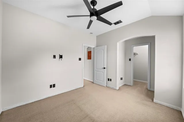 an empty room with chandelier fan and windows