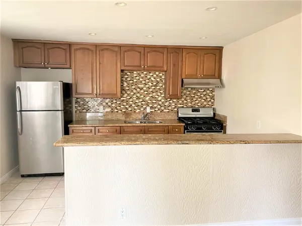 a kitchen with stainless steel appliances granite countertop a refrigerator a stove and a sink