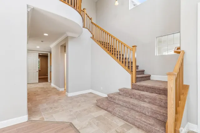 an empty room with chandelier fan and windows