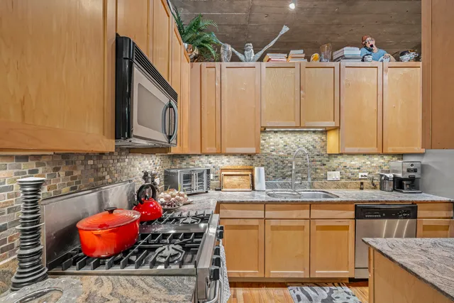 a kitchen with stainless steel appliances granite countertop a sink a stove and a wooden cabinets