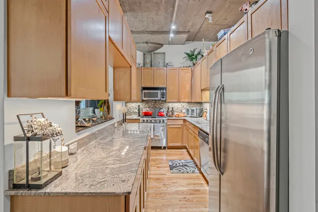a kitchen with stainless steel appliances granite countertop a refrigerator a stove and a sink