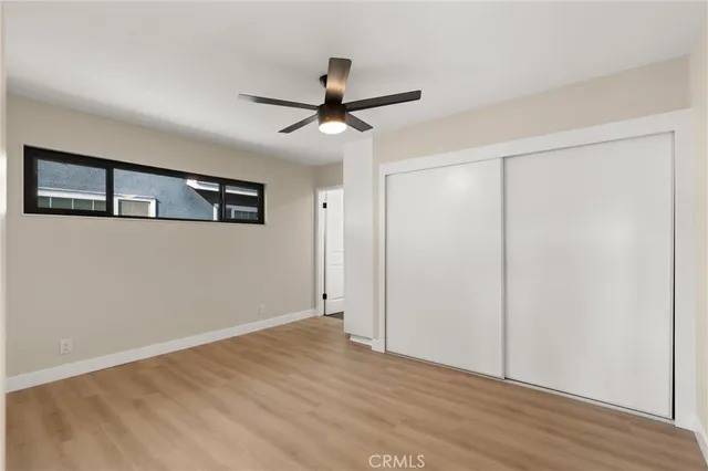 a view of empty room with wooden floor and ceiling fan