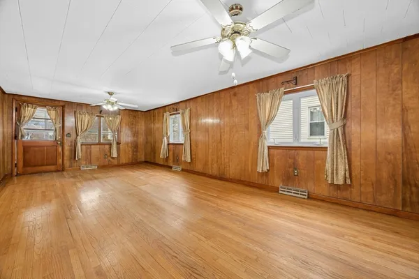 an empty room with wooden floor and windows