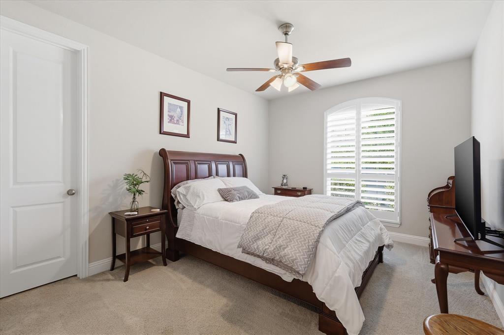 9708 Surveyor Road Oak Point, TX 75068 - Photo 25 of 34 Carpeted room featuring a white paneled door with a brushed nickel knob, an arched window with white plantation shutters, a ceiling fan with wood-finish blades, and light-toned walls
