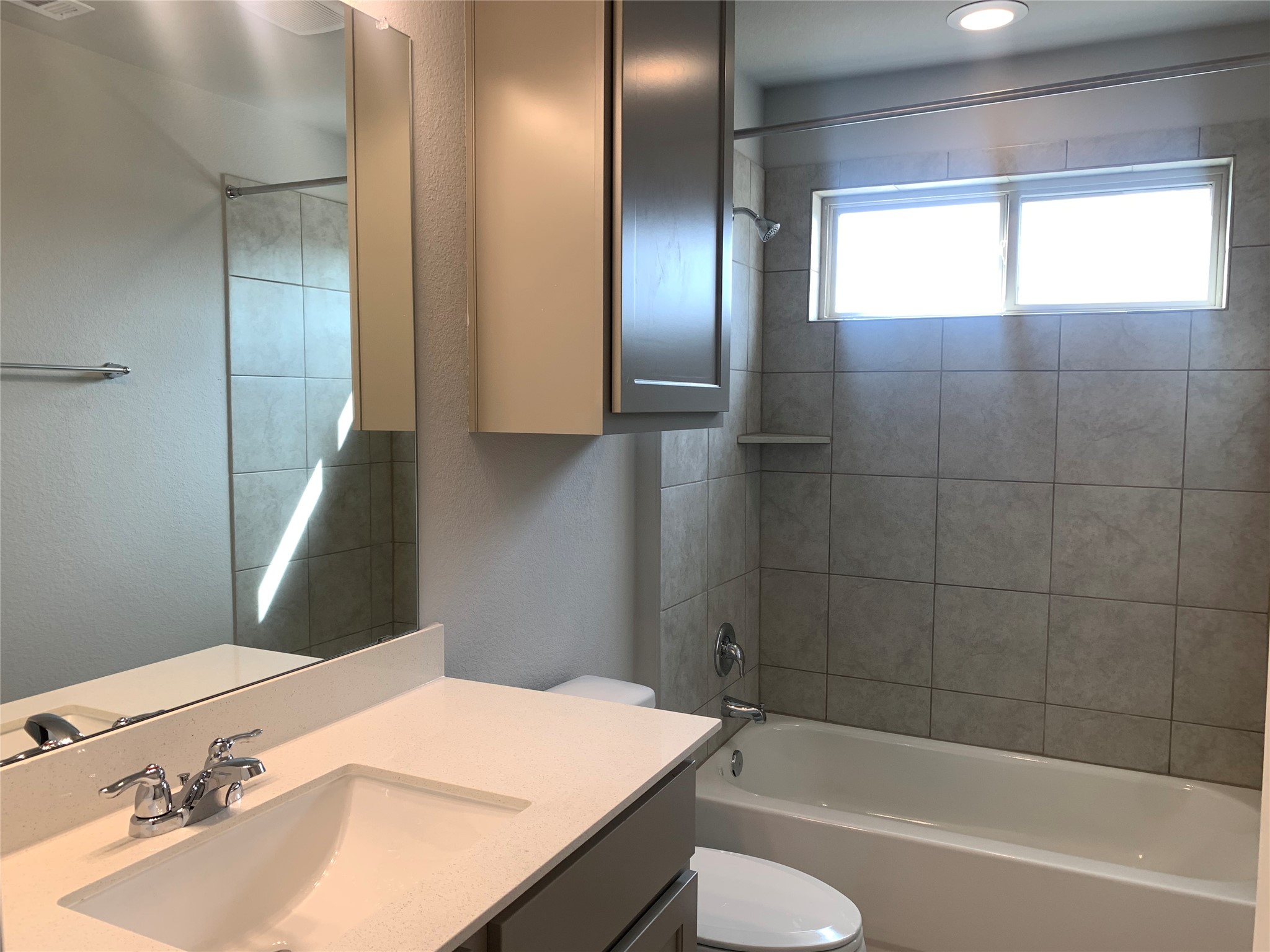 2948 Sage Ranch Drive Leander, TX 78641 - Photo 20 of 28 A well-lit bathroom features a vanity with sleek counters, complementing the tiled bath and shower area.