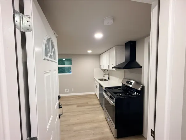 a large kitchen with a stove a sink dishwasher and a refrigerator with wooden floor