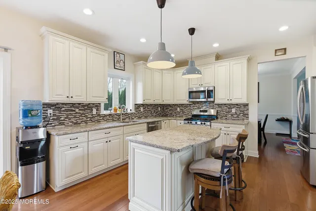 a kitchen with kitchen island a dining table chairs stainless steel appliances and cabinets