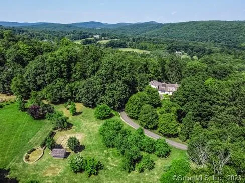 an aerial view of residential house with outdoor space and trees all around