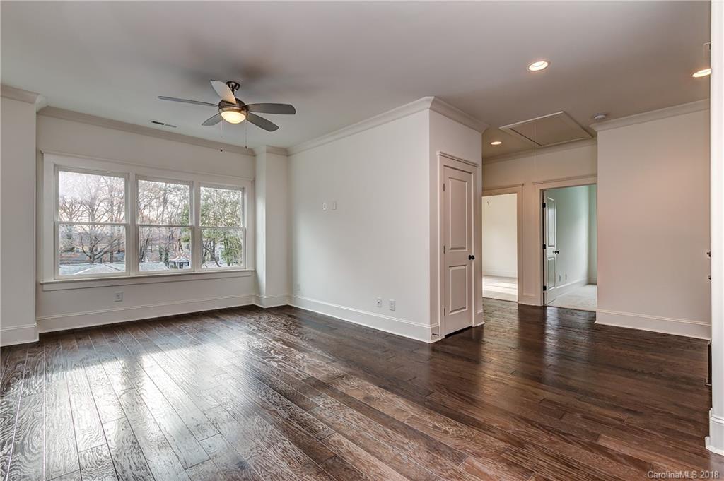748 Ellsworth Road, Unit 47 Charlotte, NC 28211 - Photo 24 of 34 an empty room with wooden floor chandelier fan and windows