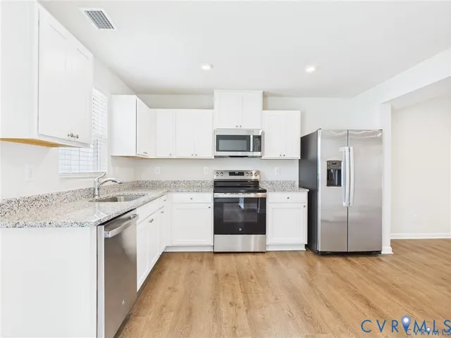 a kitchen with white cabinets stainless steel appliances and sink