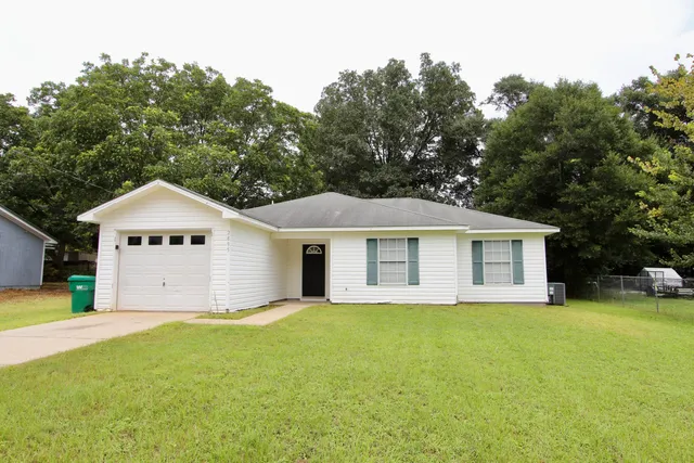 a view of a house with a yard and large trees