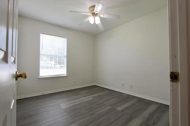 an empty room with a window and a fan